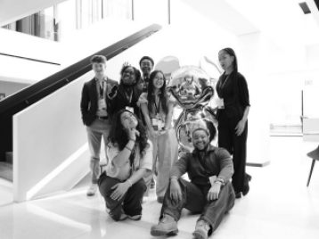 UM students grouped around a life sized metallic Micky Mouse statue